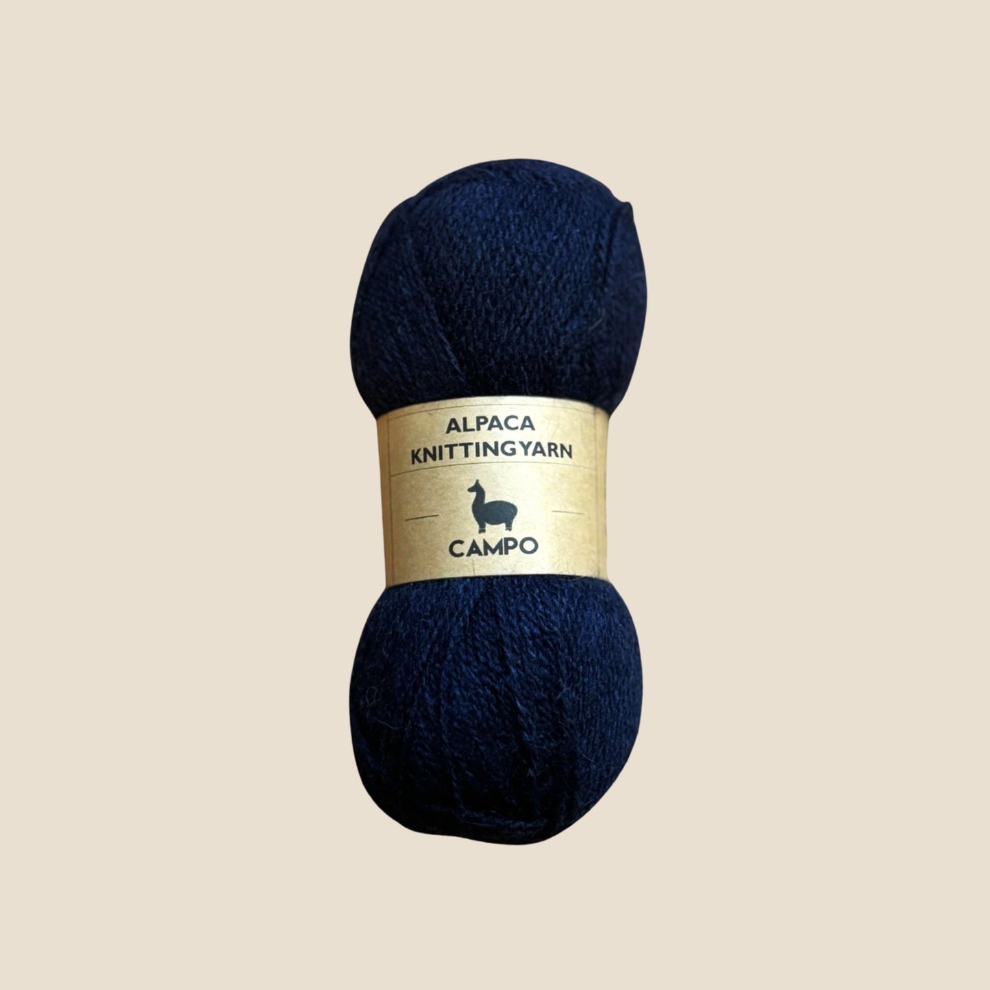Navy blue alpaca knitting yarn with a gold label on a beige background