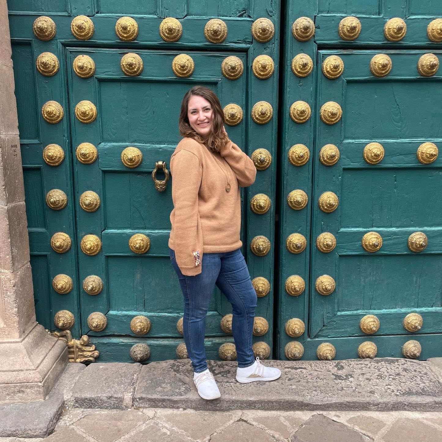 Woman standing in front of a large green door with gold studs