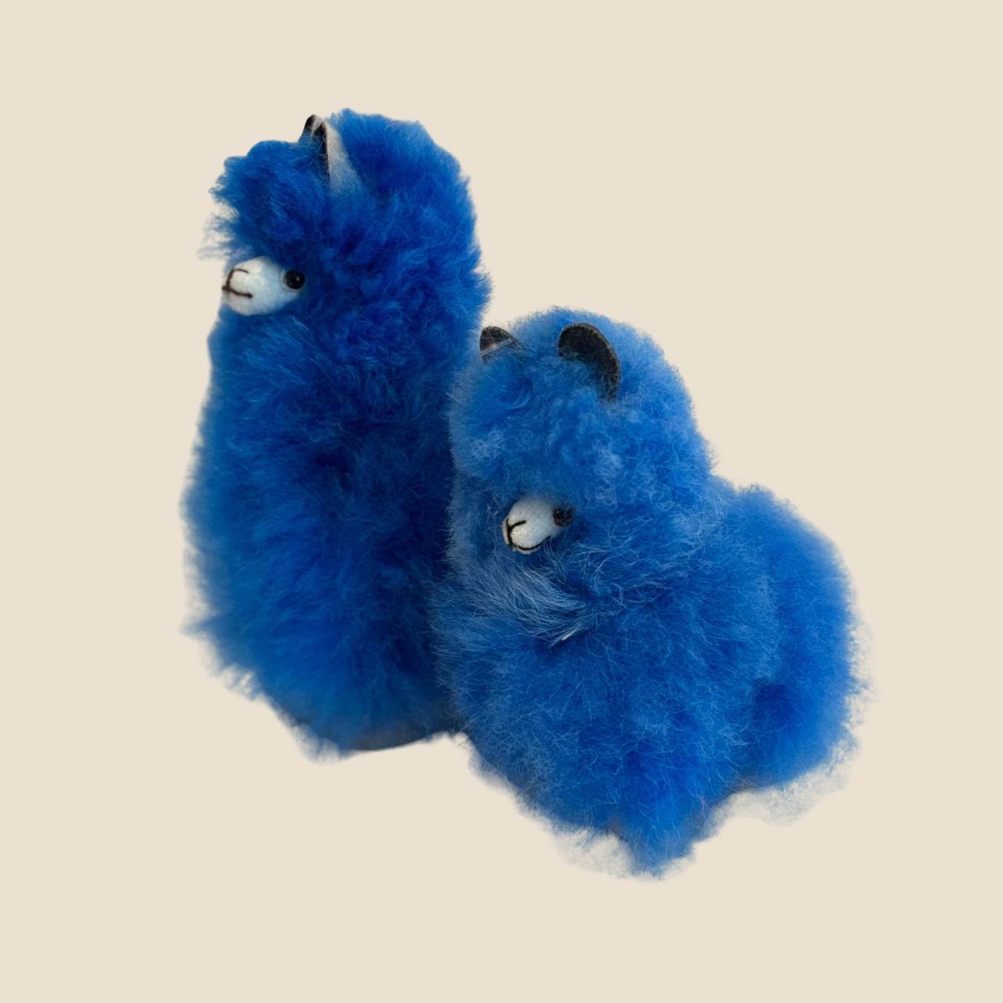 Two blue plush toys alpaca on a beige background