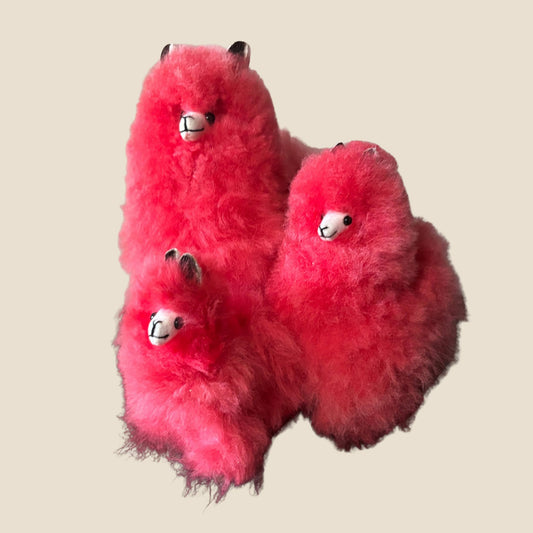Three fluffy red shaped like alpaca on a beige background