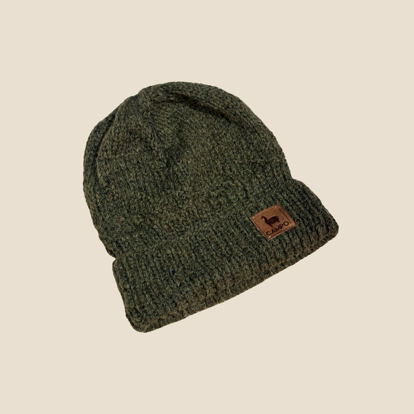 Green knit beanie with a brown label on a beige background