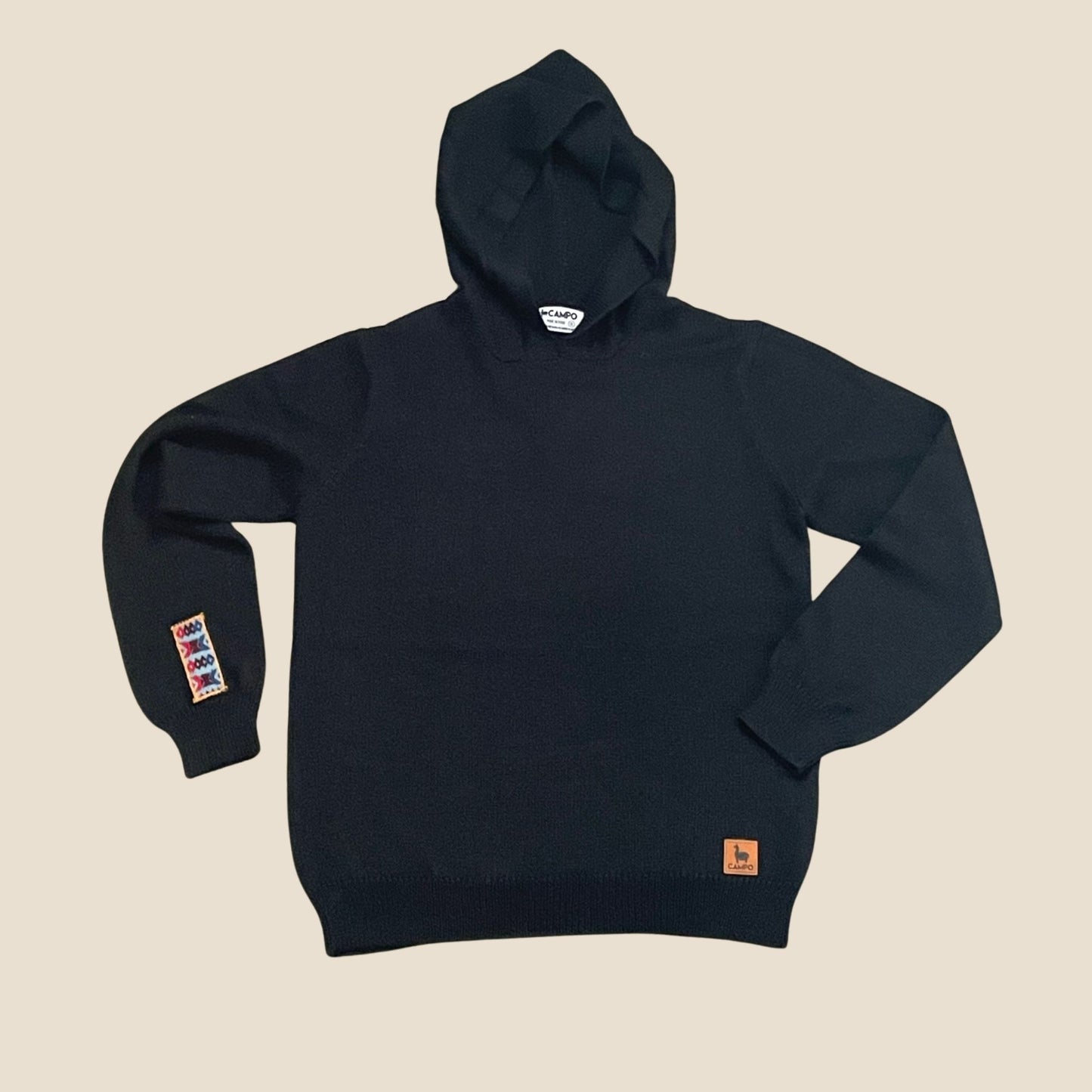 Black hoodie with visible branding on a beige background