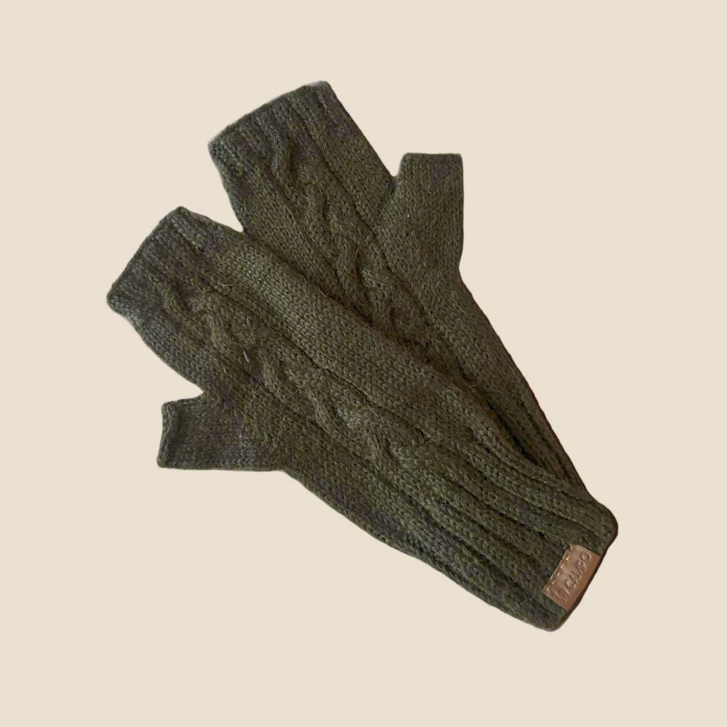 Pair of green knitted gloves on a beige background