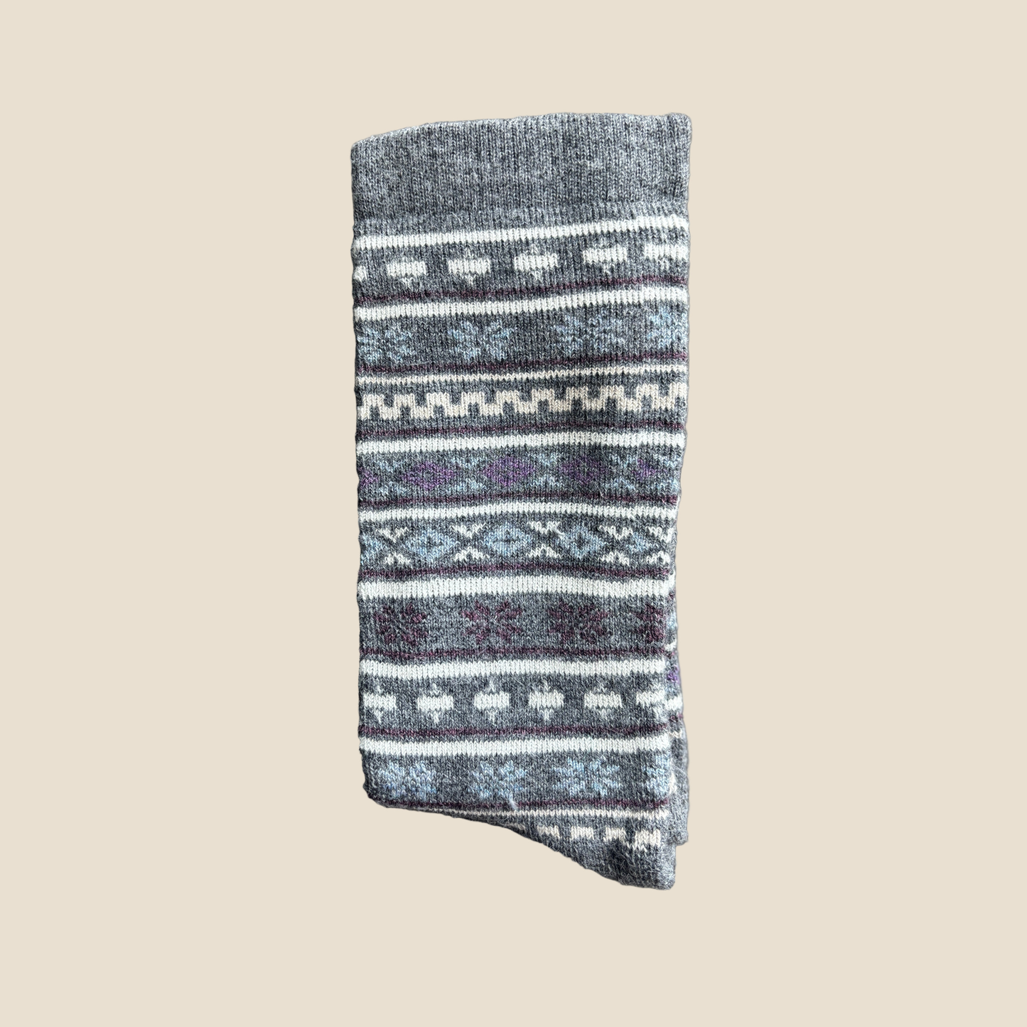 Folded knitted sock with a pattern on a beige background