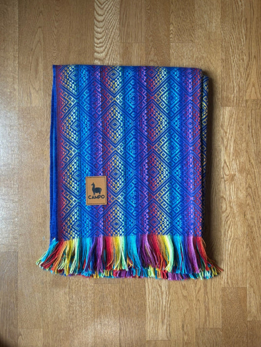 Colorful woven blanket with a brand logo on a wooden surface