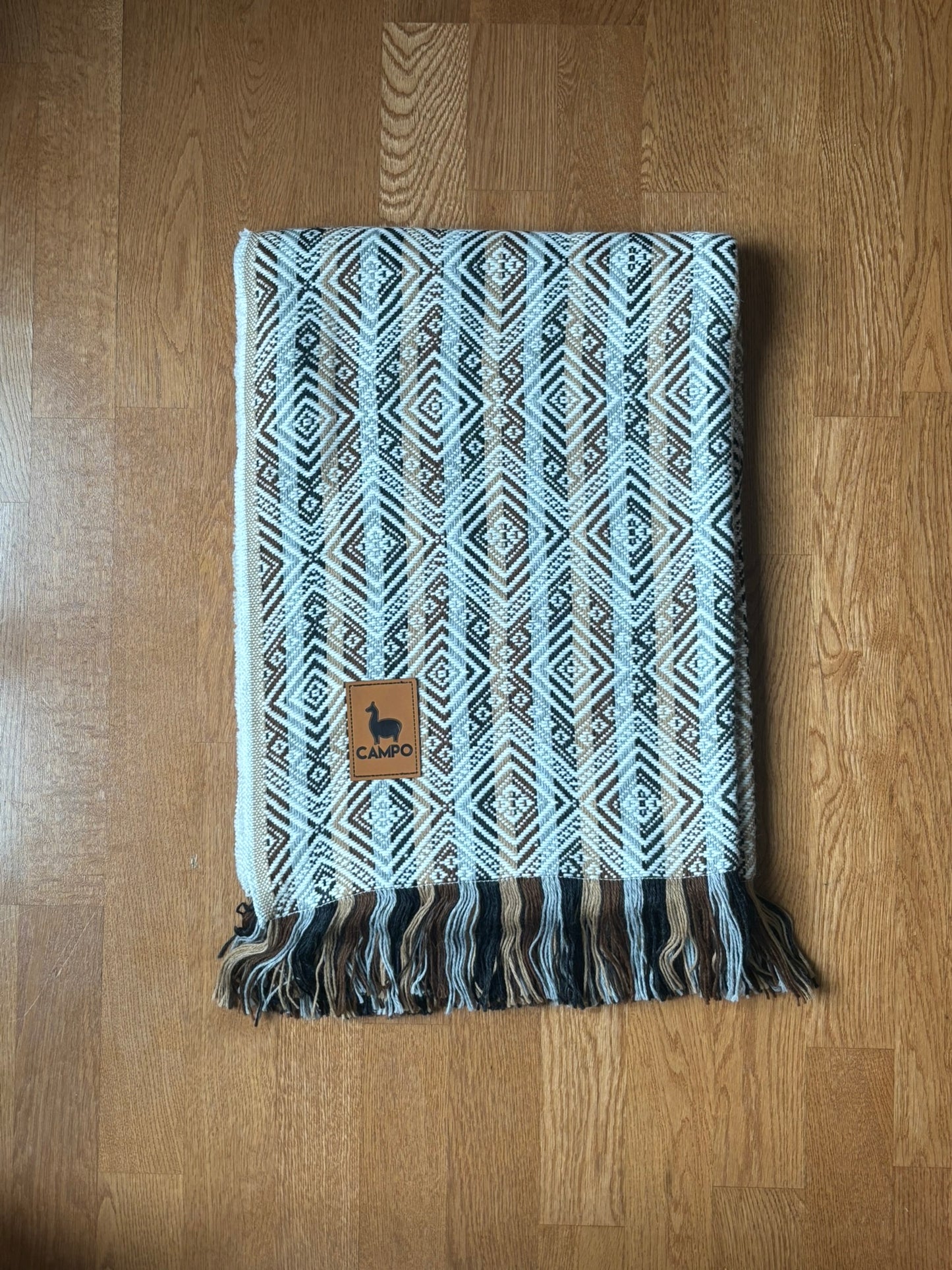 White Natural woven blanket with a brand logo on a wooden surface