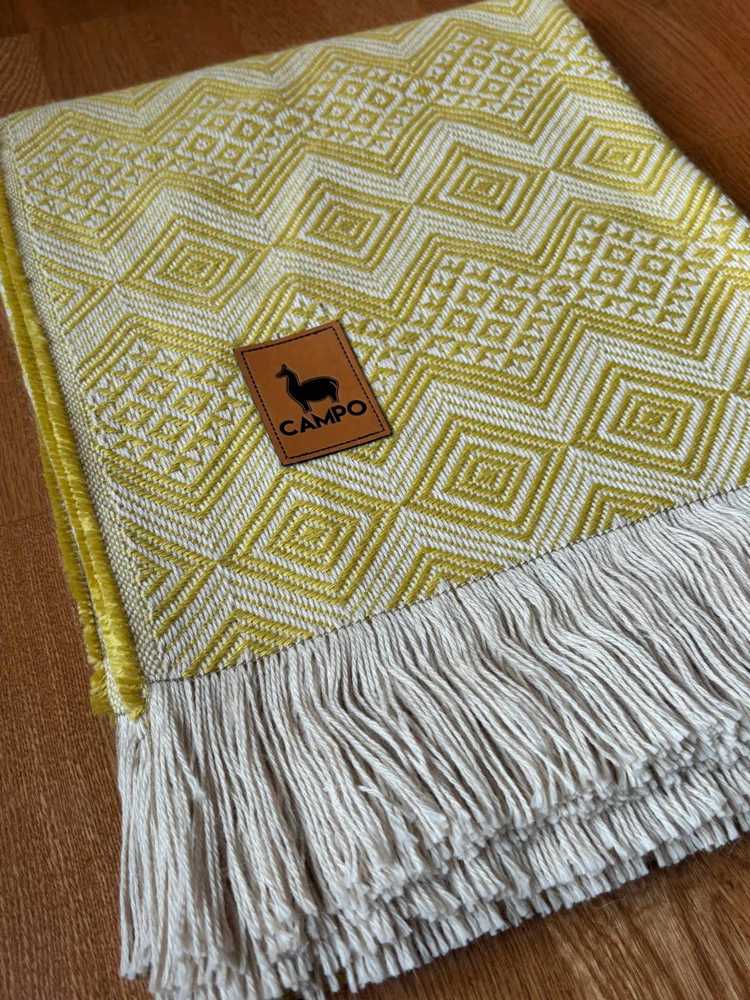 Close-up woven blanket with a brand logo on a wooden surface