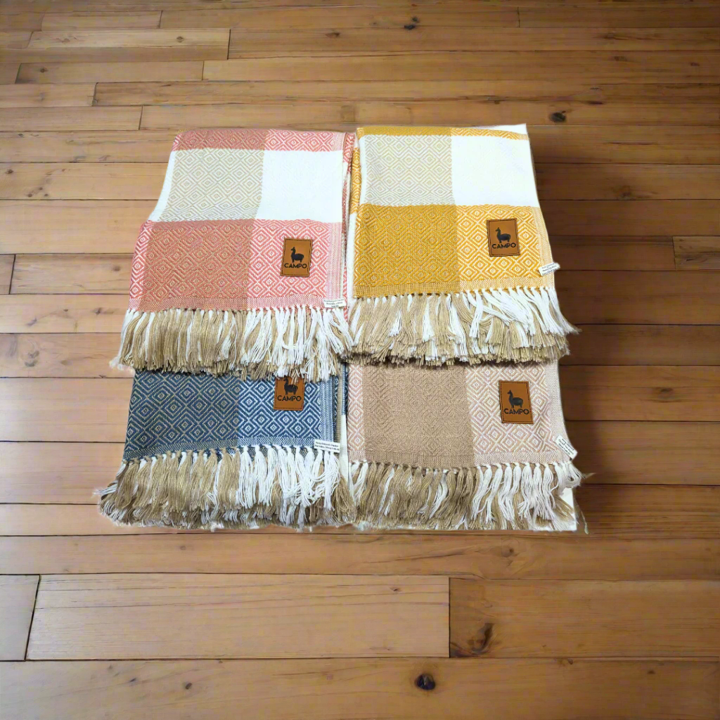 Four alpaca blend throw blankets in different colors with diamond checkered design and fringes, displayed on a white background.