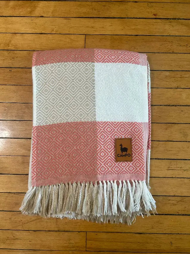 Checkered blanket with fringes on a wooden floor