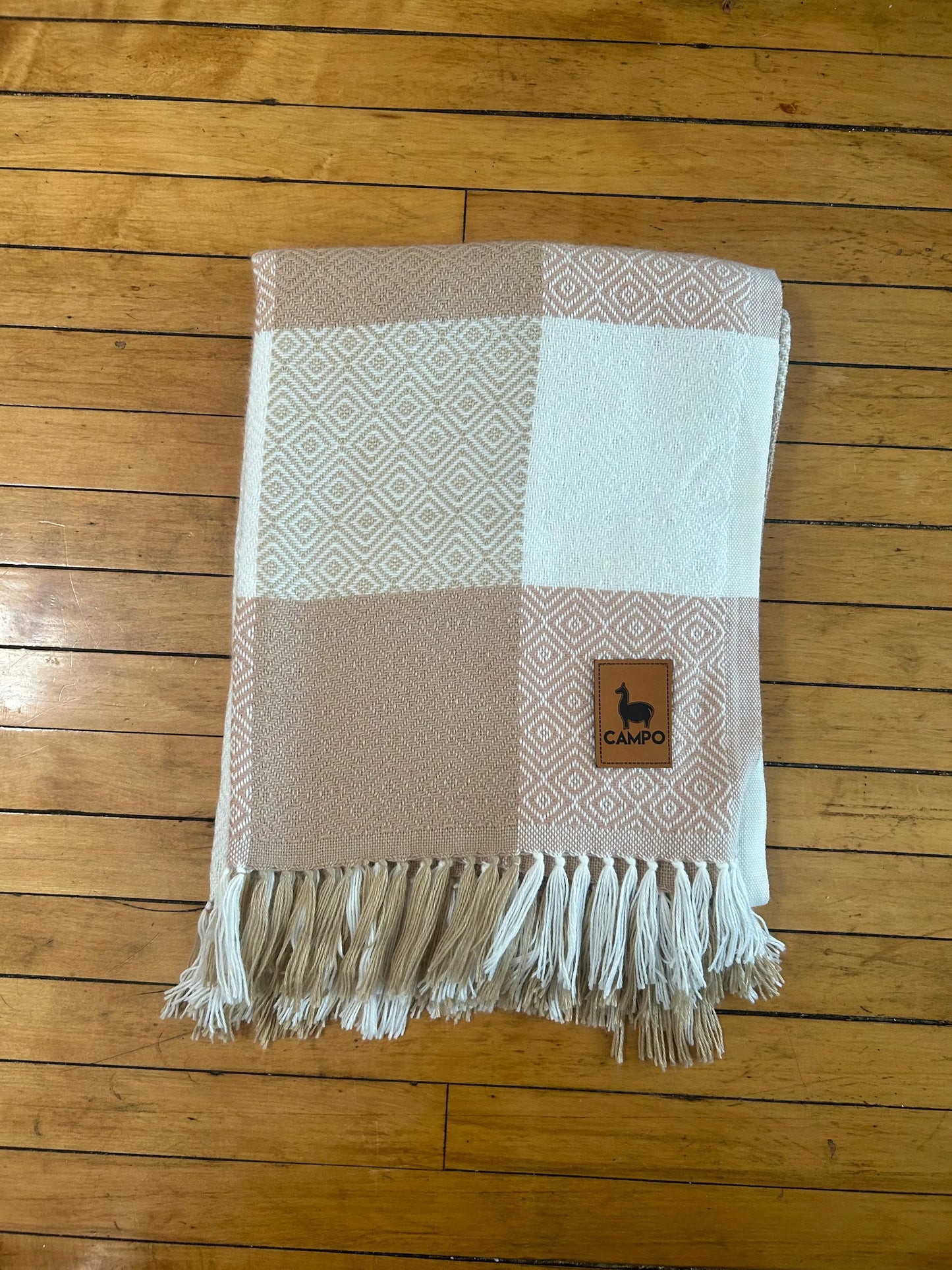 Checkered blanket with fringes on a wooden floor