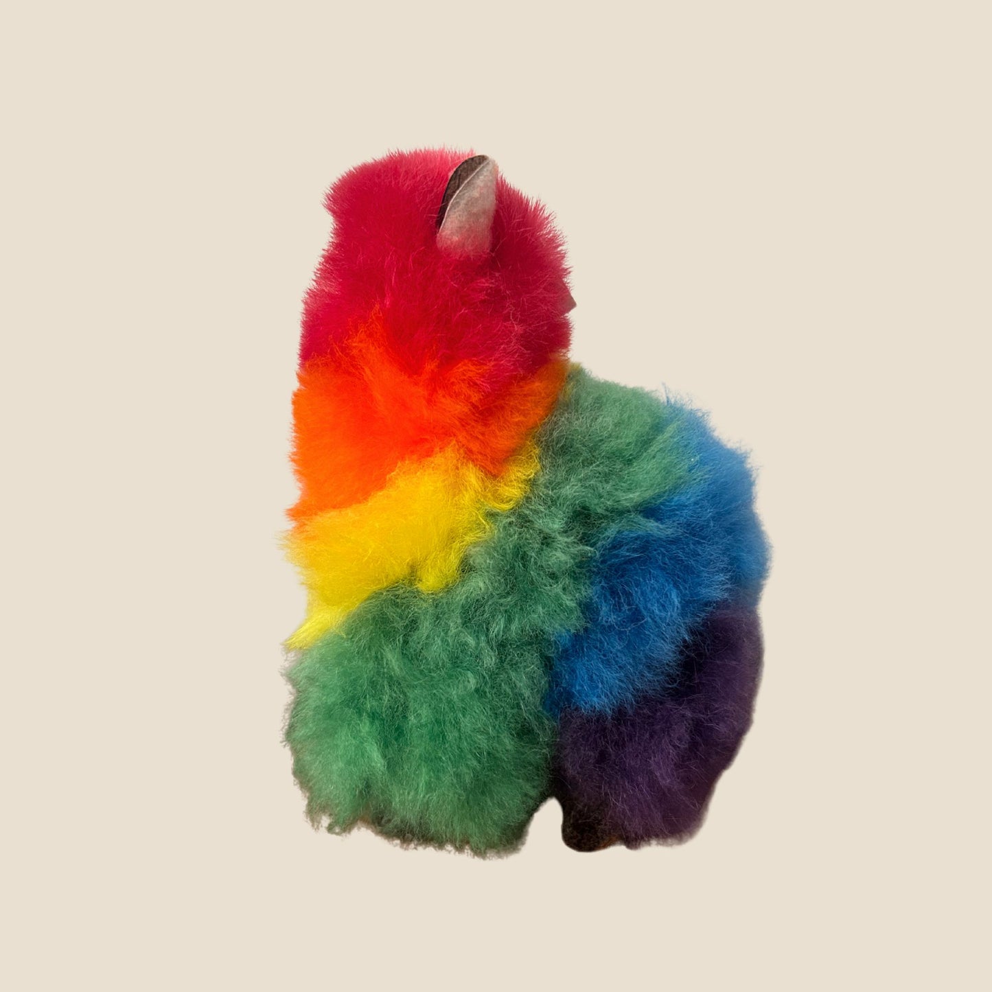 Colorful plush toy resembling a alpaca on a beige background
