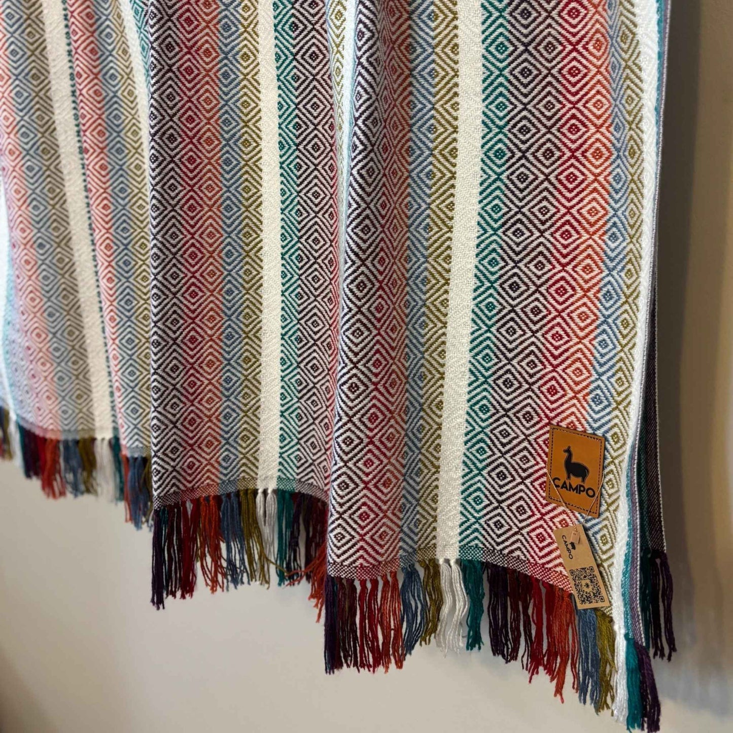 White multi woven fabric with geometric pattern and fringes, featuring a brand tag.