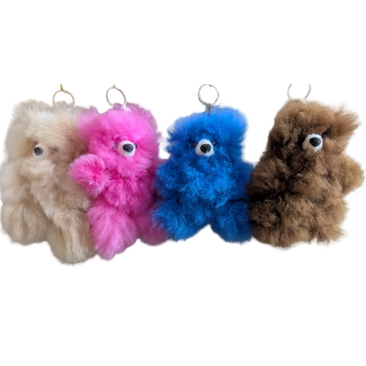 Four colorful plush toys hanging against a beige background