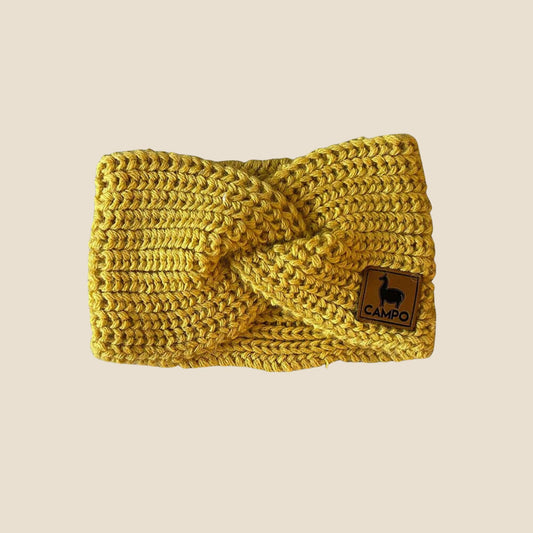 Mustard knitted headband with a brand logo on a beige background