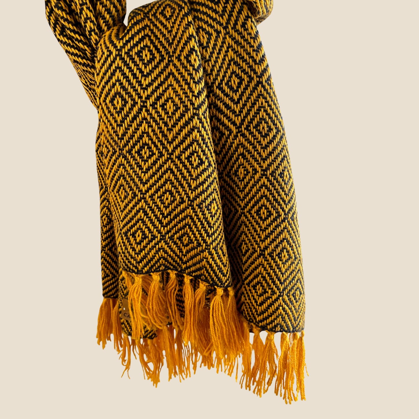 Yellow and blue patterned scarf with fringes on a beige background