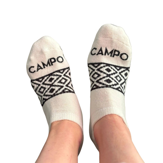 White socks with black geometric patterns and 'CAMPO' branding on a beige background