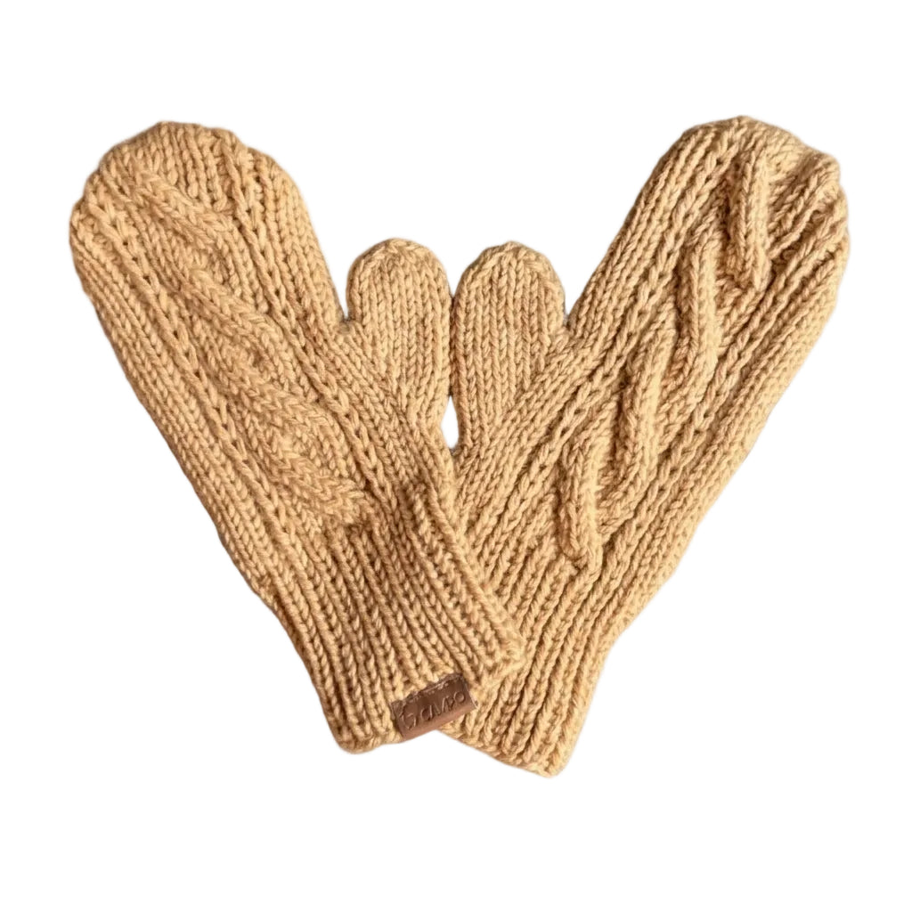 A pair of chunky cable-knit mittens in a warm camel tan color, arranged overlapping on a solid light beige background.