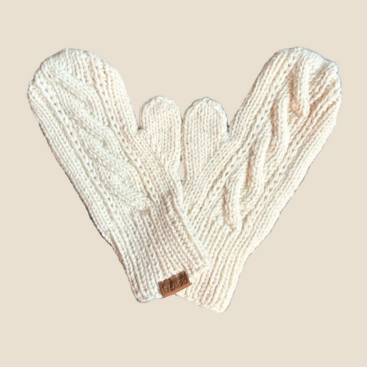 Pair of beige knitted mittens on a wooden surface