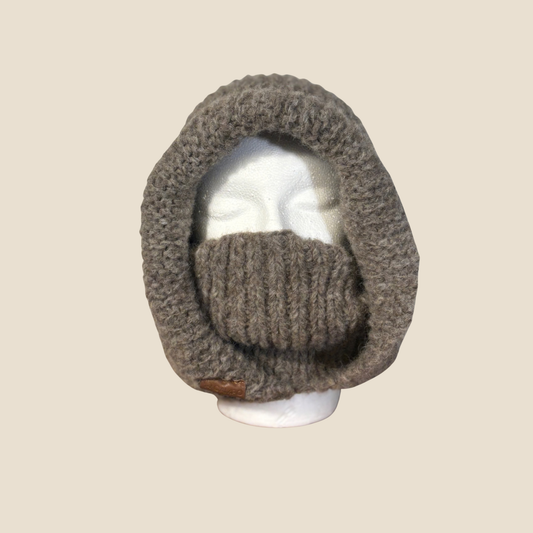 Knitted balaclava on a mannequin head against a beige background
