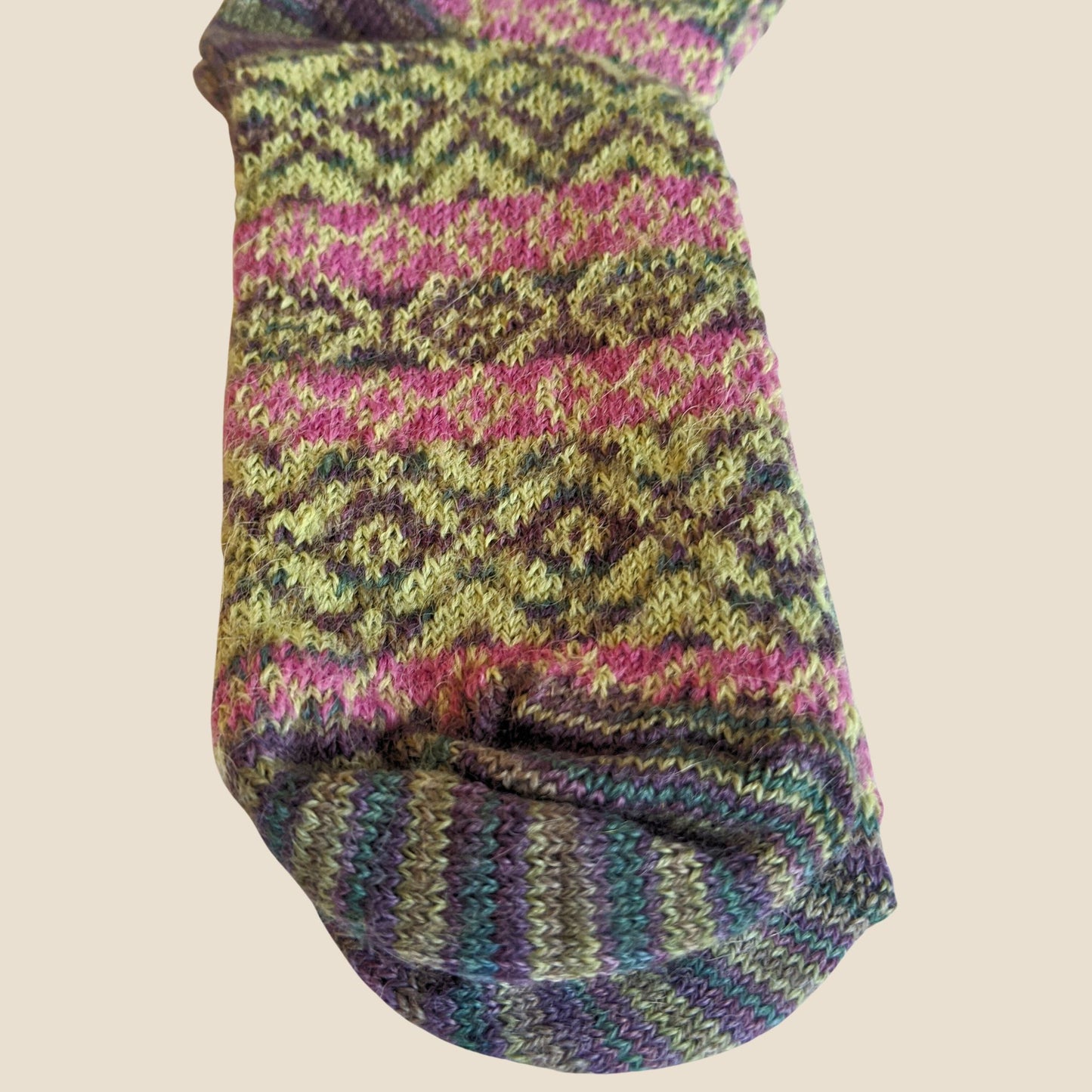 Multicolored knitted sock on a beige background