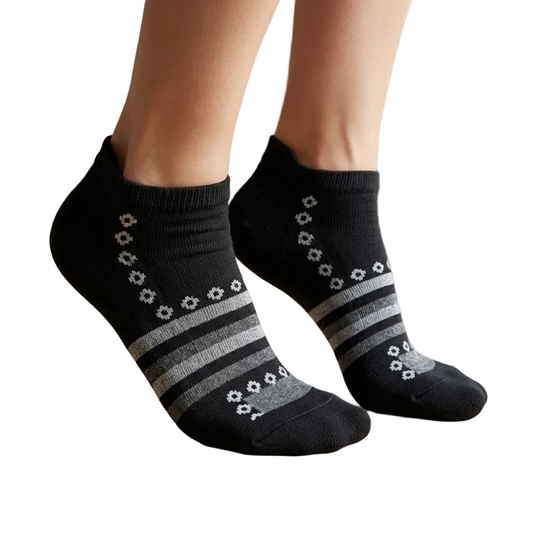 Black socks with gray stripes worn by a person on a wooden floor.