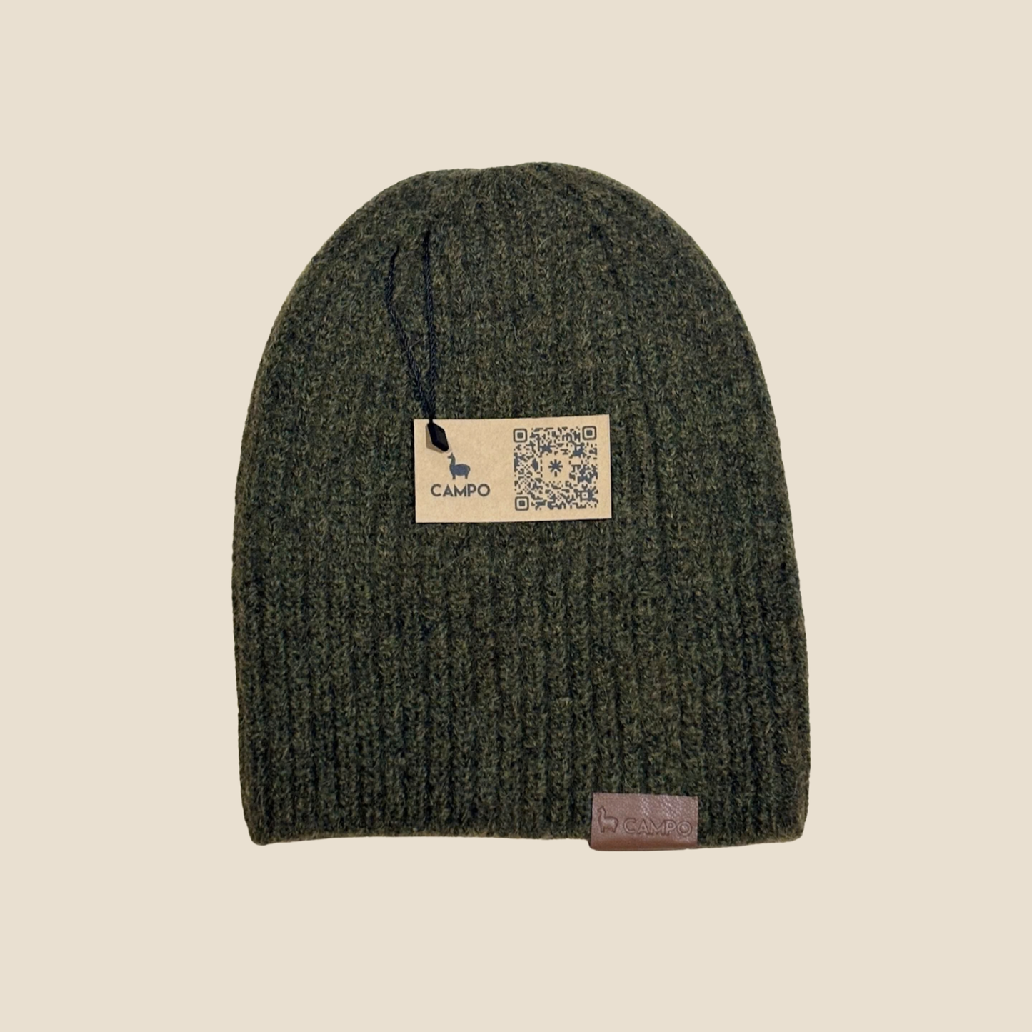 Green knit beanie with a brand label on a beige background