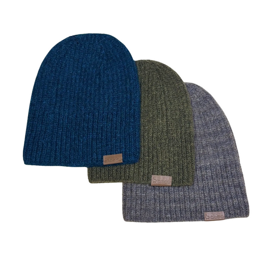 Three knit beanie hats in blue, green, and gray on a beige background