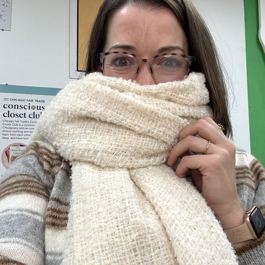 Person wearing a large white scarf over their face with a blurred background