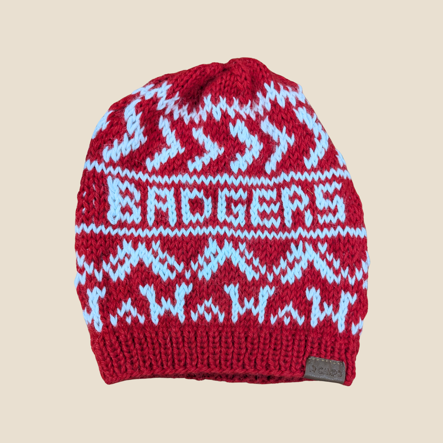 Red knit beanie with white and blue pattern on a beige background