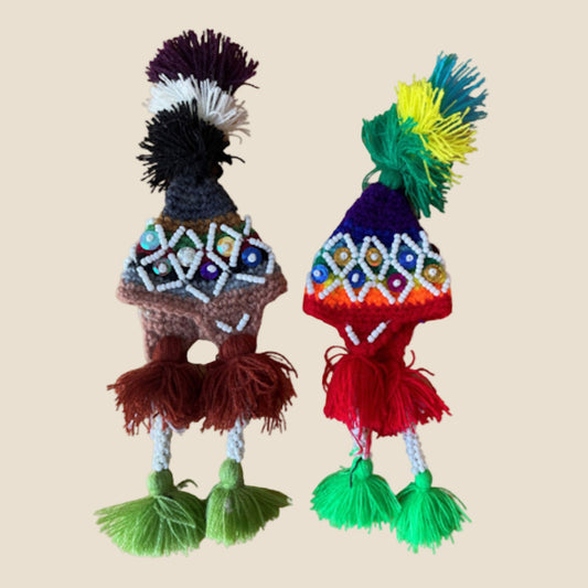 Two colorful handcrafted toys with intricate patterns on a beige background