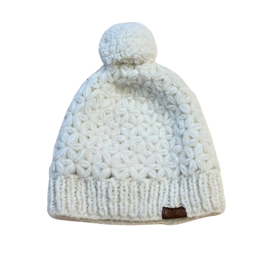White knit beanie with a pom-pom on a beige background