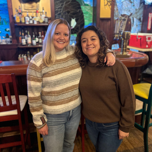 Two women posing together wearing striped alpaca and brown alpaca