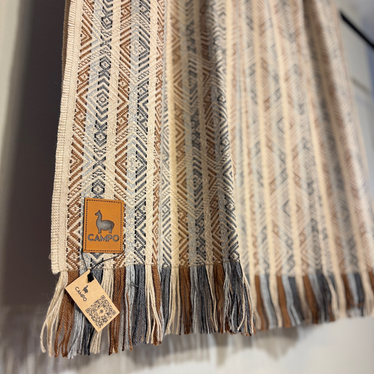 Textured scarf with tassels and a visible brand tag on a neutral background