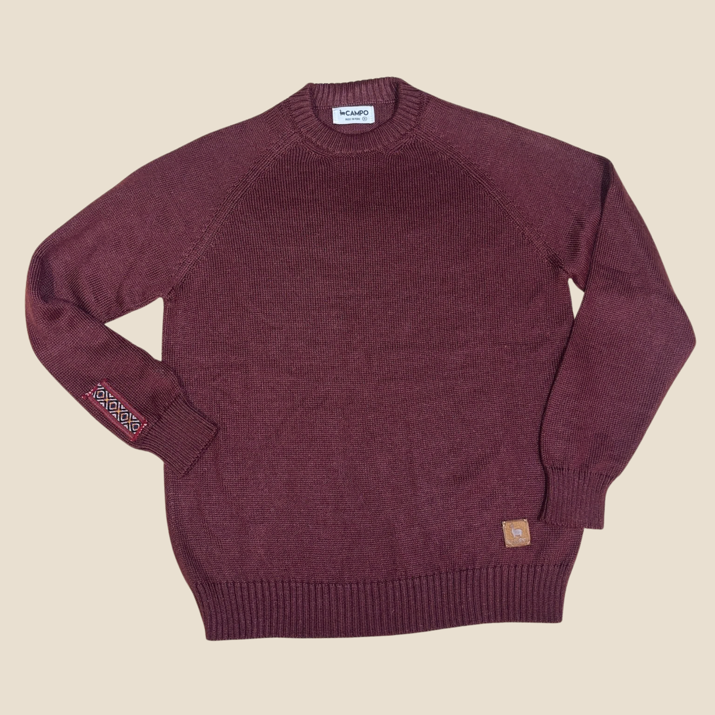 Merlot sweater with brand labels on a beige background