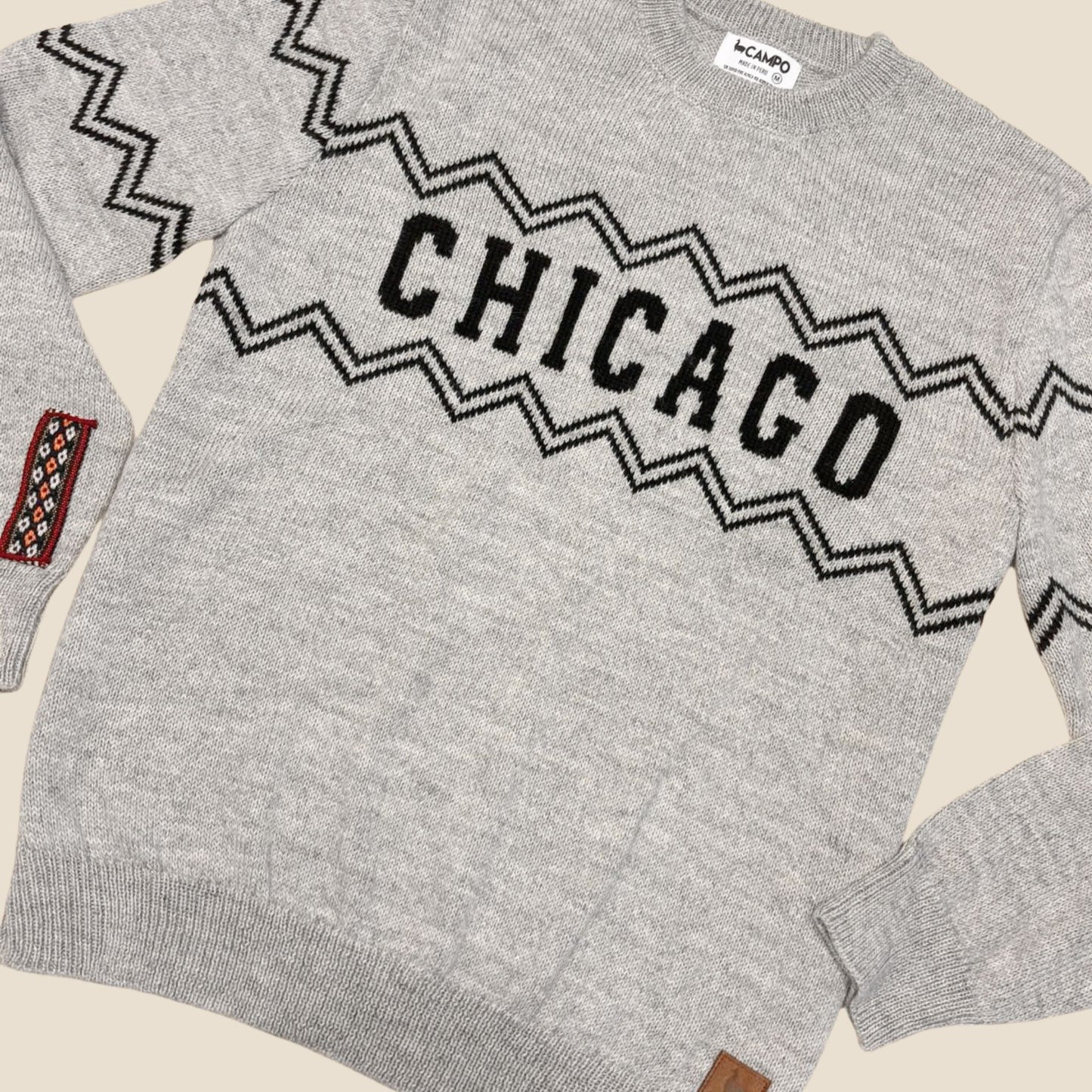 Gray sweater with 'Chicago' text and geometric pattern on a beige background