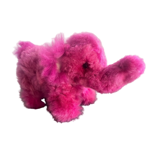 Pink plush elephant toy on a dark surface with a light gray background