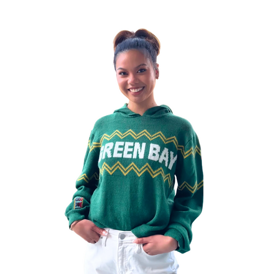 Person wearing a green 'Green Bay' sweater on a beige background