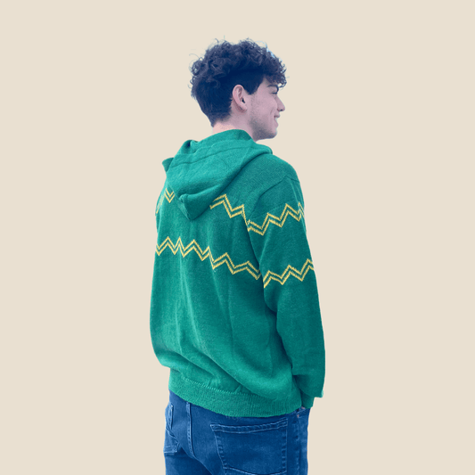 Person wearing a green hoodie with yellow zigzag pattern on a beige background
