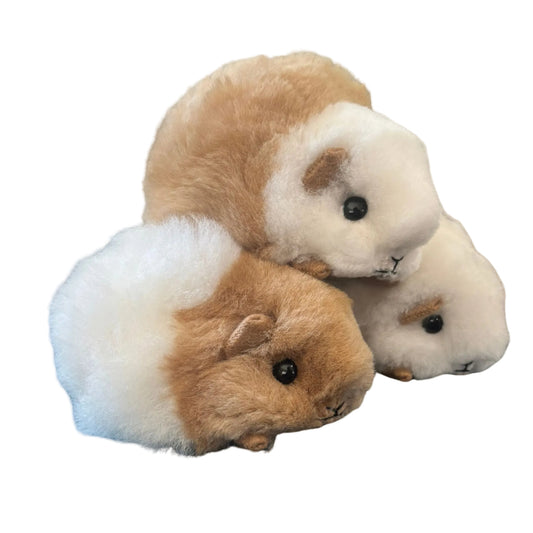 Three plush toy guinea pigs on a beige background
