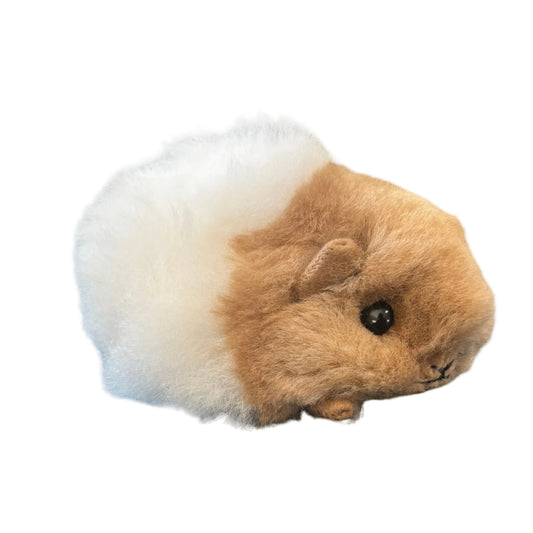 Plush toy resembling a guinea pig with a white bottom and brown top on a beige background