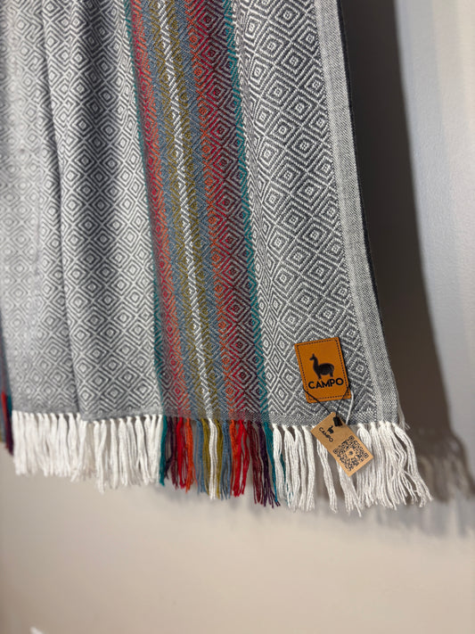 Textured scarf with geometric pattern and fringes, featuring a brand tag.