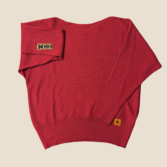 Red off shoulder sweater with brand labels on a beige background