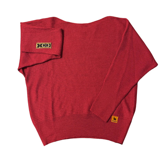 Red off shoulder sweater with brand labels on a beige background