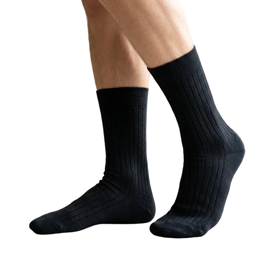 Person wearing black socks indoors with a neutral background