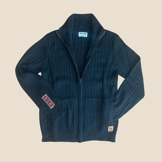 Black sweater with a patterned patch on a beige background