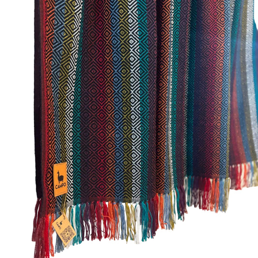 Black multi woven blanket with geometric patterns and fringes on a light background