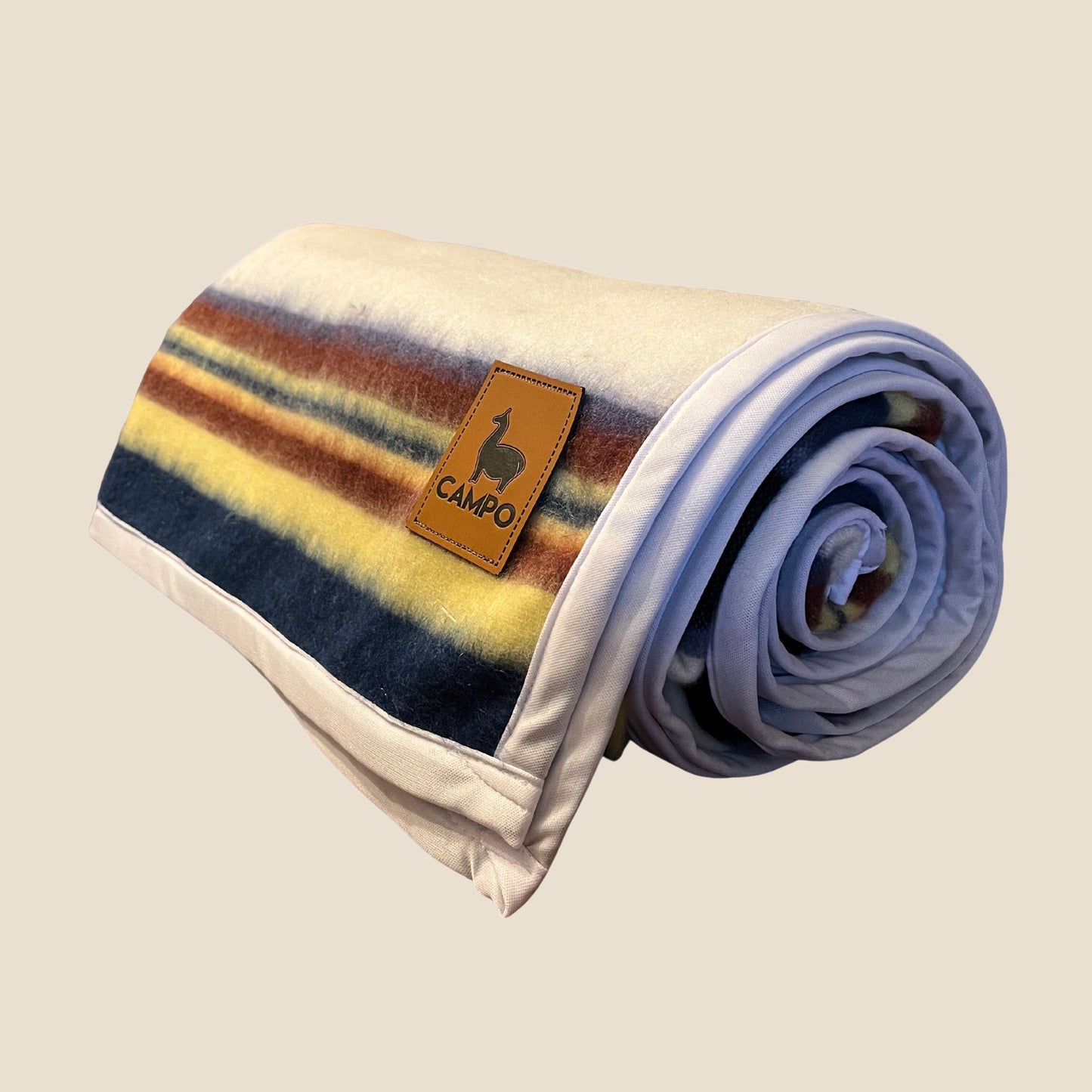 Rolled-up blanket with striped pattern and 'Campo' logo on a beige background