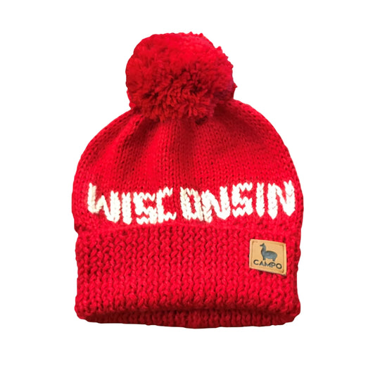 Red knit beanie with 'WISCONSIN' text and a pom-pom on a beige background