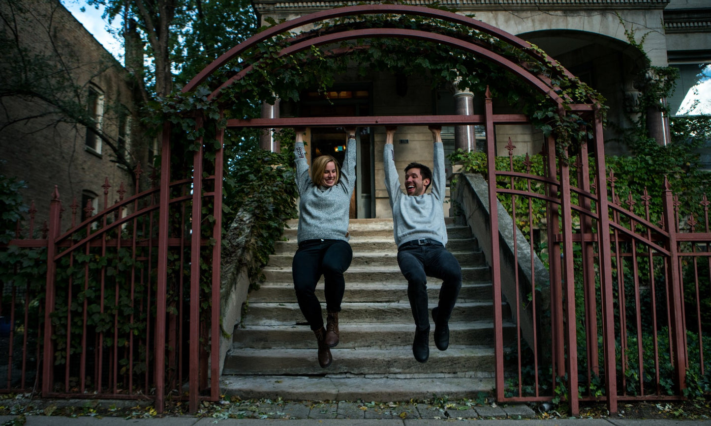 People hanging on gate outside and smiling wearing salt and pepper alpaca crew neck sweater