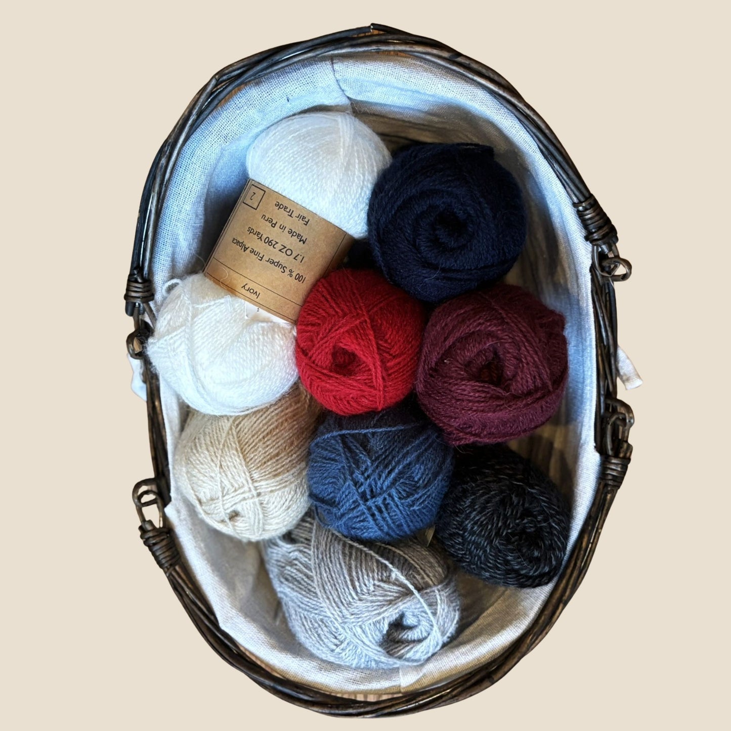 Basket filled with various colored yarn balls on a beige background